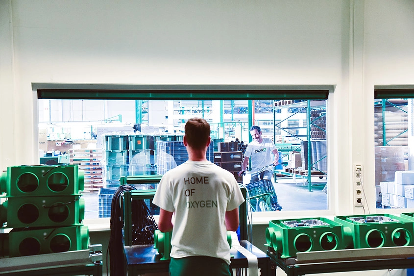 A person with short hair is seen from the back wearing a white shirt with