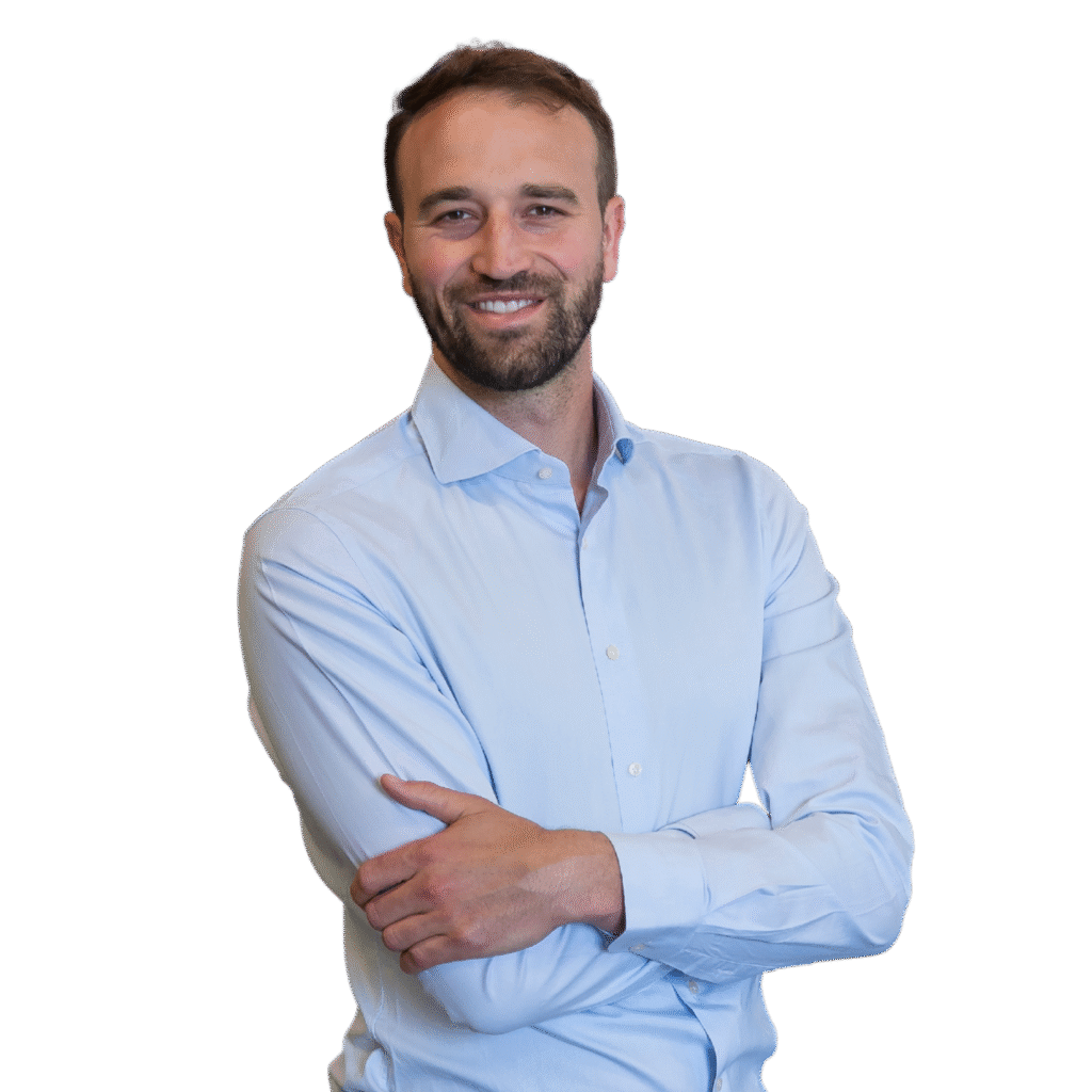 Jan Billen, Plant Manager at e-power, standing with a confident smile. He is wearing a light blue button-up shirt, grey trousers, and a brown belt, with his arms crossed and body slightly turned. The background is transparent.